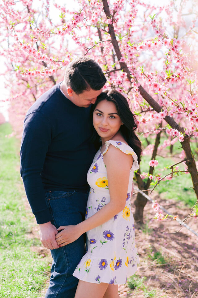 Man and woman snuggling in pink orchard