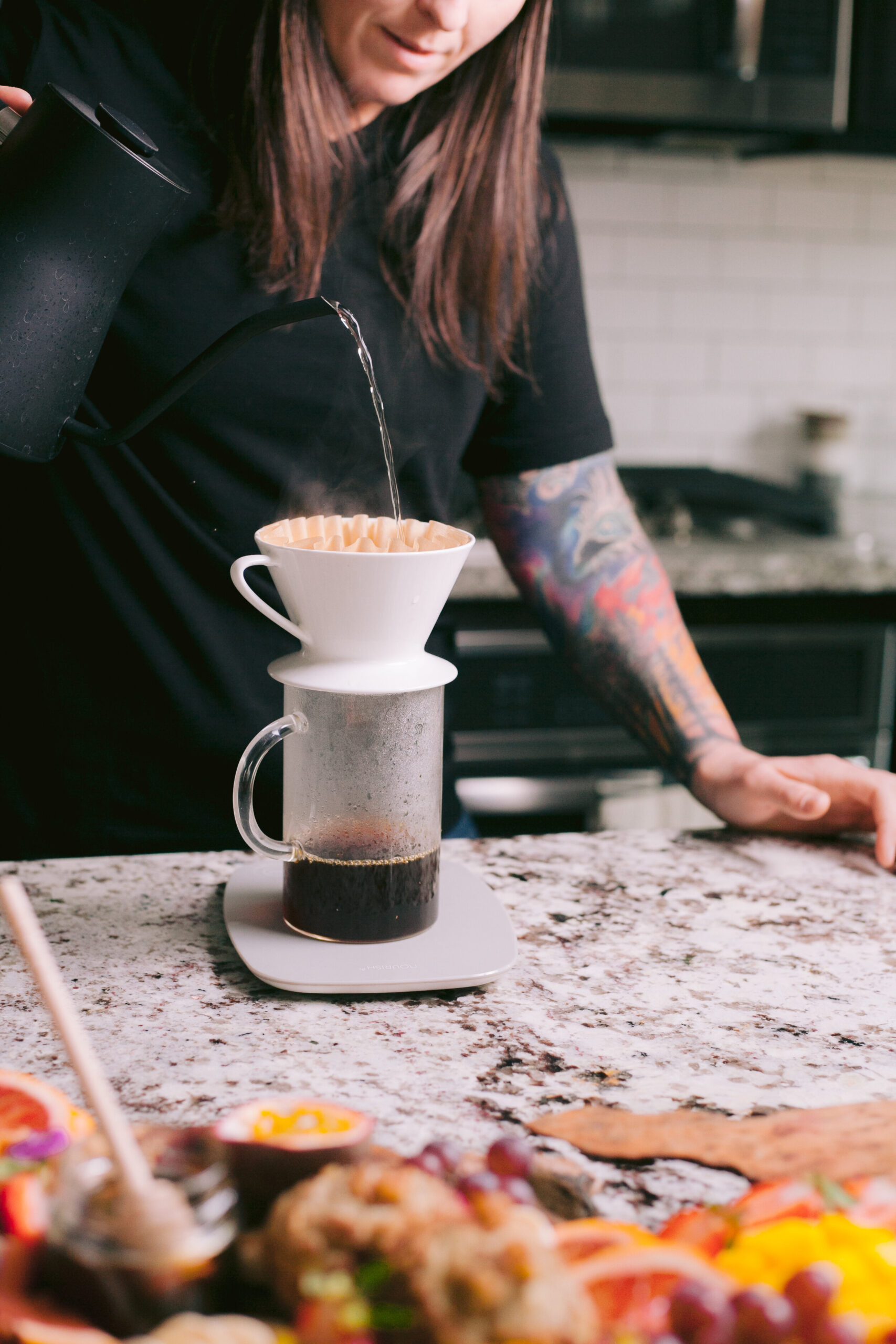  Woman pouring hot water over pour over brewer in kitchen. 