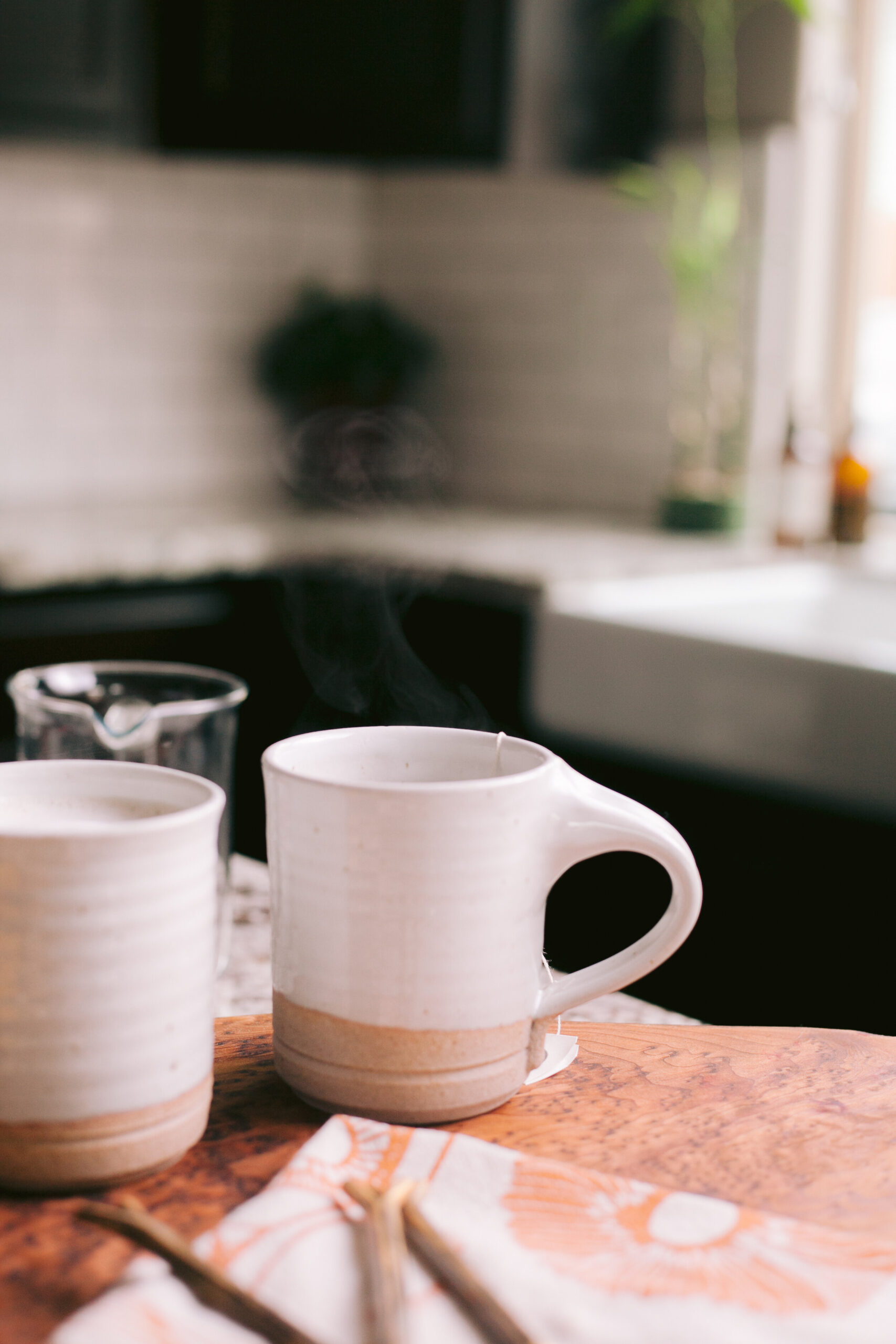  Two steaming hot cups of coffee on kitchen island.  