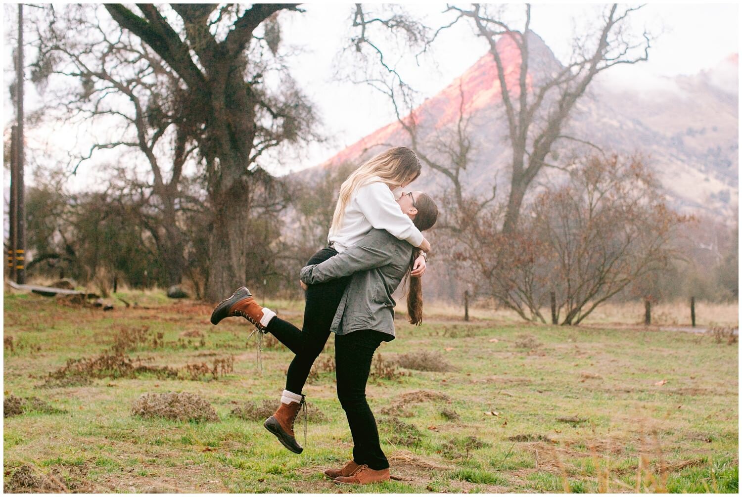 Two women embracing in front of mountain
