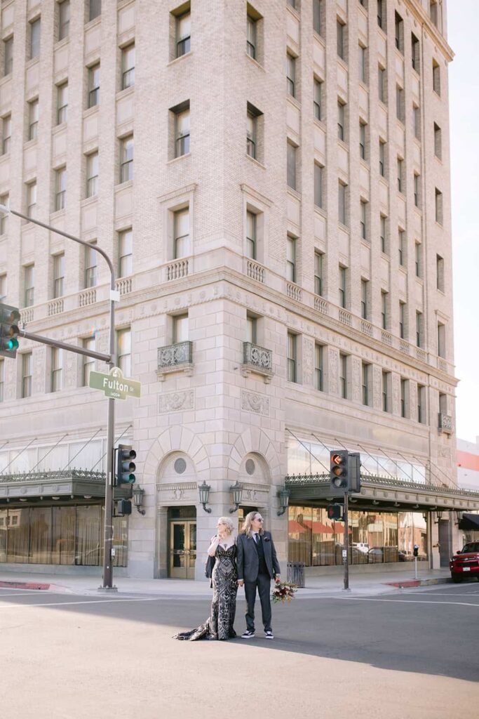 Couple crossing the street in downtown Fresno after courthouse wedding Bride and groom crossing a downtown Fresno street, holding hands and bouquet