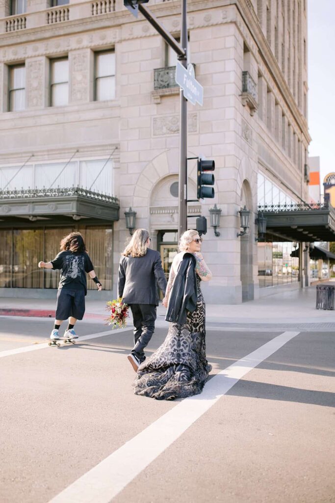 Couple crossing the street in downtown Fresno after courthouse wedding Bride and groom crossing a downtown Fresno street, holding hands and bouquet