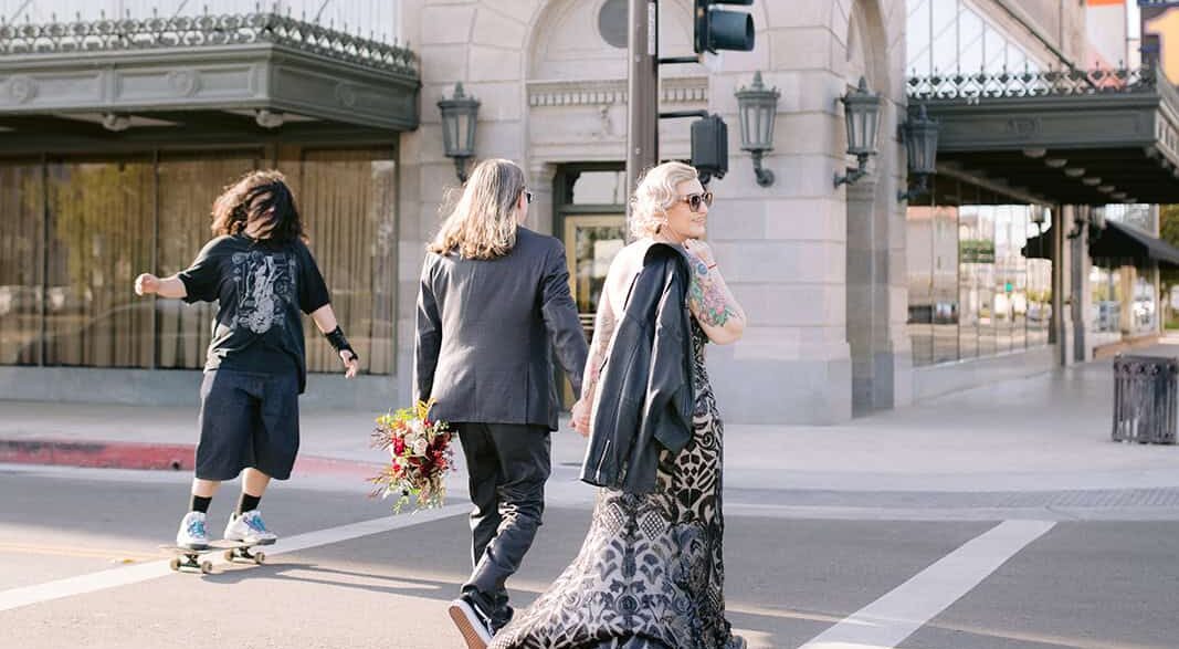 Bride and groom walking across crosswalk in downtown fresno with a skateboarder traveling the other direction