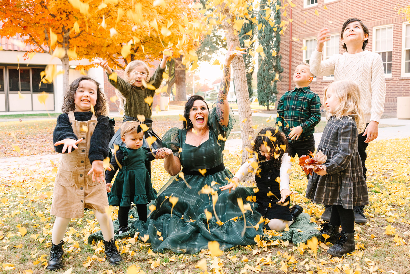 Family and children playing in fall leaves at Fresno City College, one of the best places to take photos in Fresno, CA