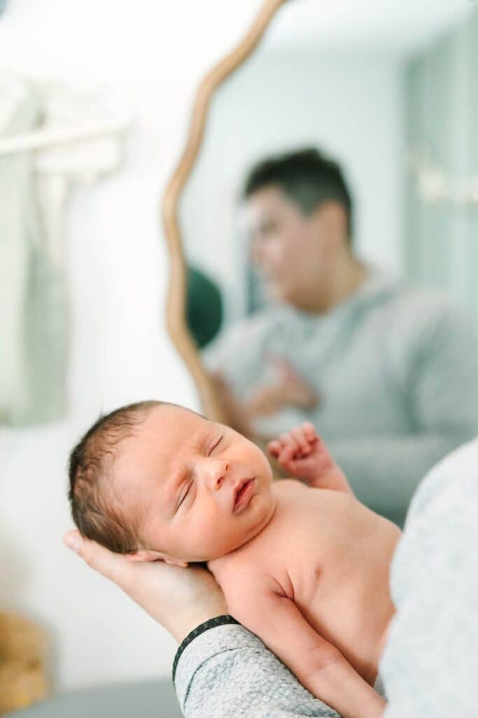 Close-up of a newborn sleeping peacefully in someone’s arms during a Fresno family photo session, emphasizing closeness and comfort from Fresno family photo tips.