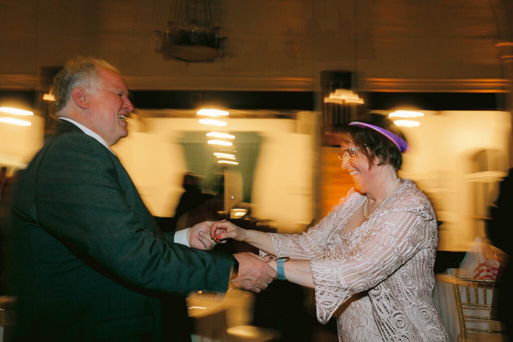 Guests hold hands and dance with motion blur on the reception floor at a Berkley City Club wedding, captured by Michelle Gunn Photo during a lively lesbian wedding celebration.