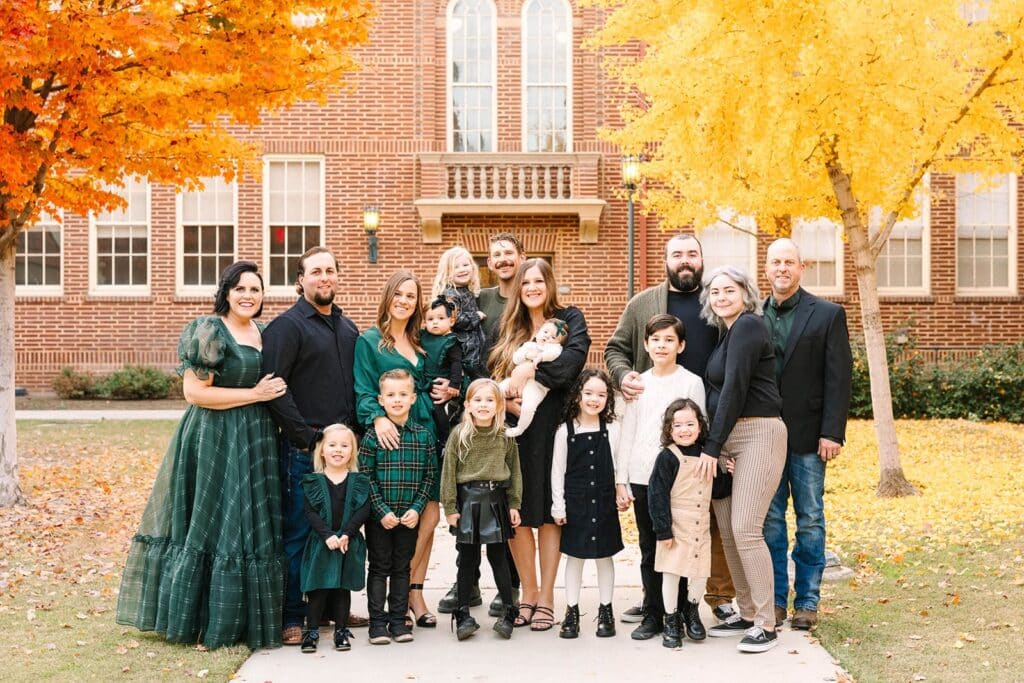 An extended family standing in small groups along a walkway lined with bright autumn trees during a Fresno family photo session, showing thoughtful spacing and balance from Fresno family photo tips.