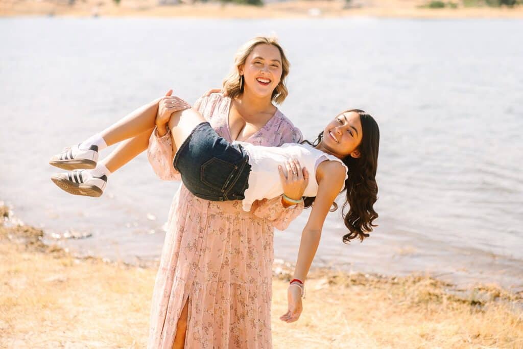 A parent playfully lifting a child near the water during a Fresno family photo session, showing playful posing ideas from Fresno family photo tips.