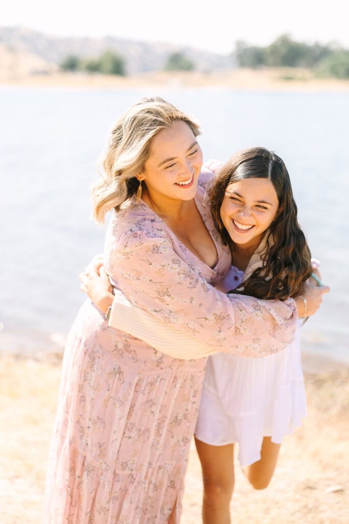 A parent hugging an older child while laughing together near the lake during a Fresno family photo session, highlighting affectionate moments from Fresno family photo tips.