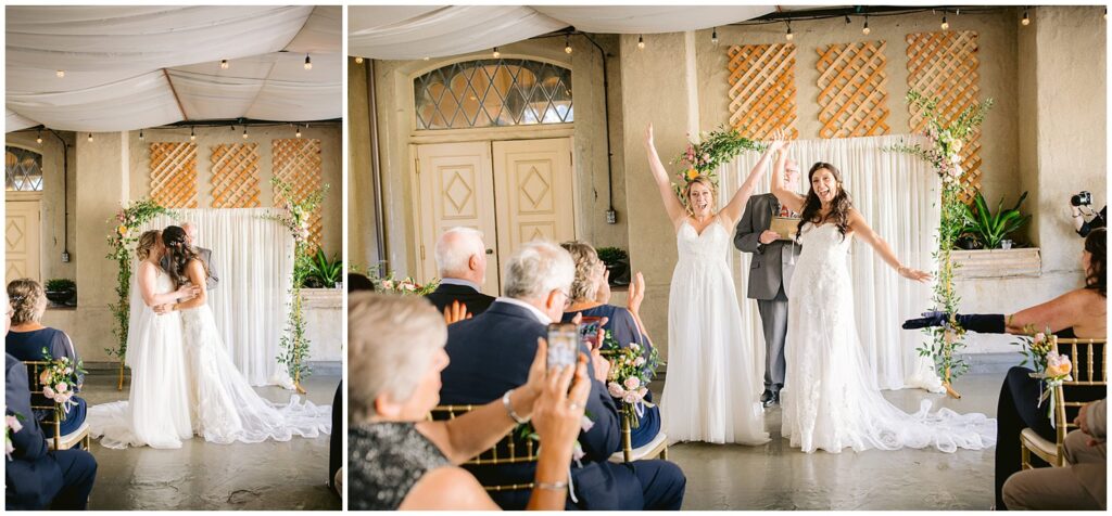 Two brides kiss beneath a floral ceremony arch and then celebrate with raised hands as guests applaud during their Berkley City Club wedding, captured by Michelle Gunn Photo at a heartfelt lesbian wedding.