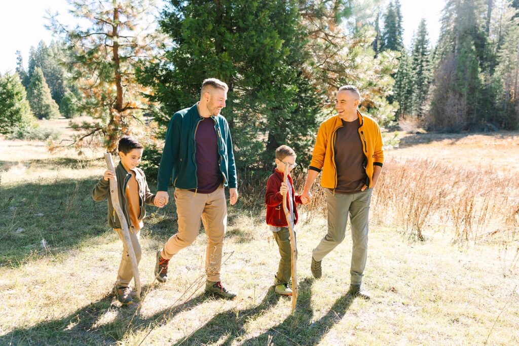 Two parents walking hand in hand with their children through a grassy field during a Fresno family photo session, demonstrating movement-based moments in Fresno family photo tips.