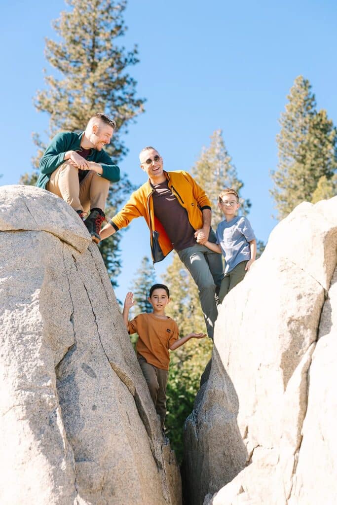 A family standing and climbing between tall rock formations during a Fresno family photo session, showcasing adventurous moments from Fresno family photo tips.