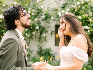 Bride wiping away tears while holding hands with groom during their vow exchange at a Fresno wedding