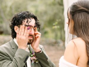 Groom wiping away tears as bride reads heartfelt vows during their emotional Fresno wedding ceremony