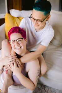 Happy LGBTQ+ couple sharing a joyful moment on the couch on their Fresno wedding day