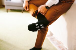 Close-up of wedding outfit detail: black sock with “Gay AF” on the bottom