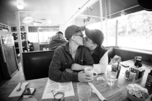 LGBTQ+ couple sharing a kiss in a cozy Fresno diner during their wedding morning