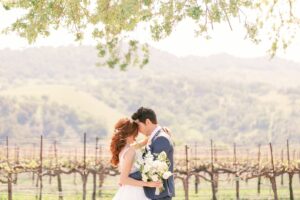Bride and groom sharing a romantic moment under the trees during their Fresno vineyard wedding