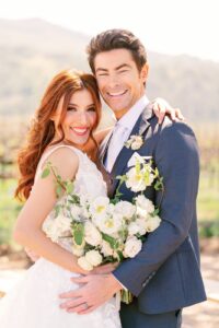 Playful and romantic pose of bride and groom holding hands and smiling during their Fresno vineyard wedding