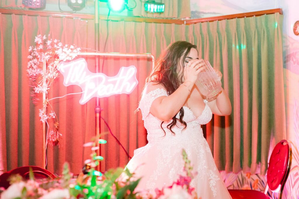 Bride pauses to hydrate during a colorful reception moment, reflecting real-life advice for wedding days about pacing yourself and staying present.