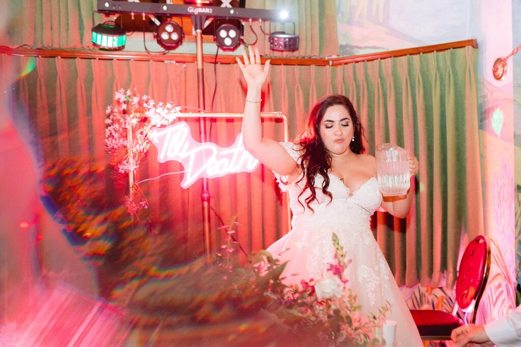 Bride pauses to hydrate during a colorful reception moment, reflecting real-life advice for wedding days about pacing yourself and staying present.