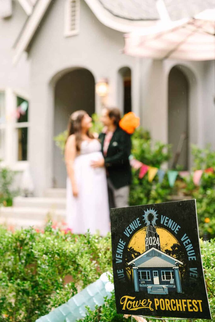 Tower Porchfest sign in front yard with couple embracing in the background at an intimate Porchfest Fresno wedding.